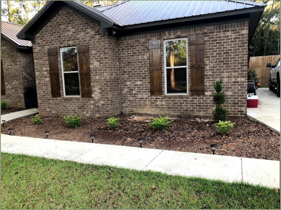 Brick home exterior with windows and a landscaped yard.